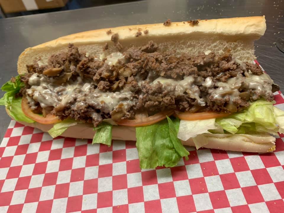 A cheesesteak with lettuce and tomato.