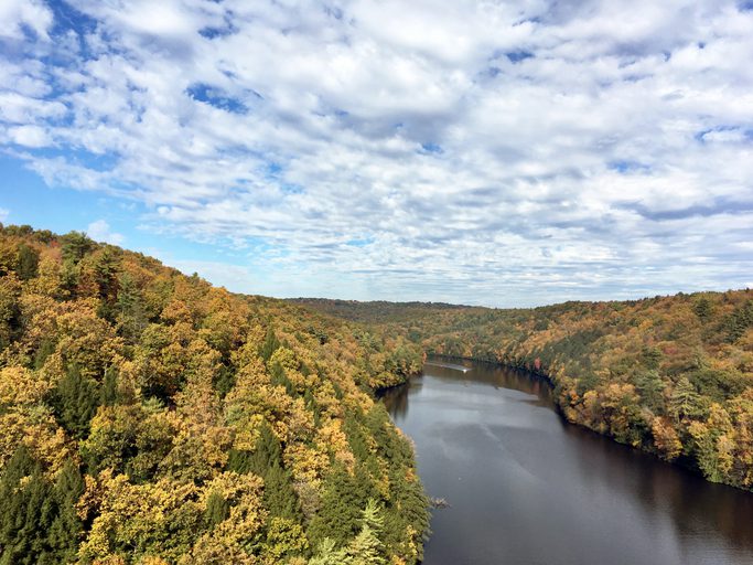 A boat travels down the Clarion River in Pennsylvania surrounded by Autumn colored trees in the month of October. This is one of the best fishing spots in PA.