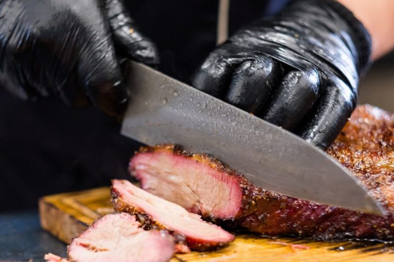 A chef cutting a piece of brisket