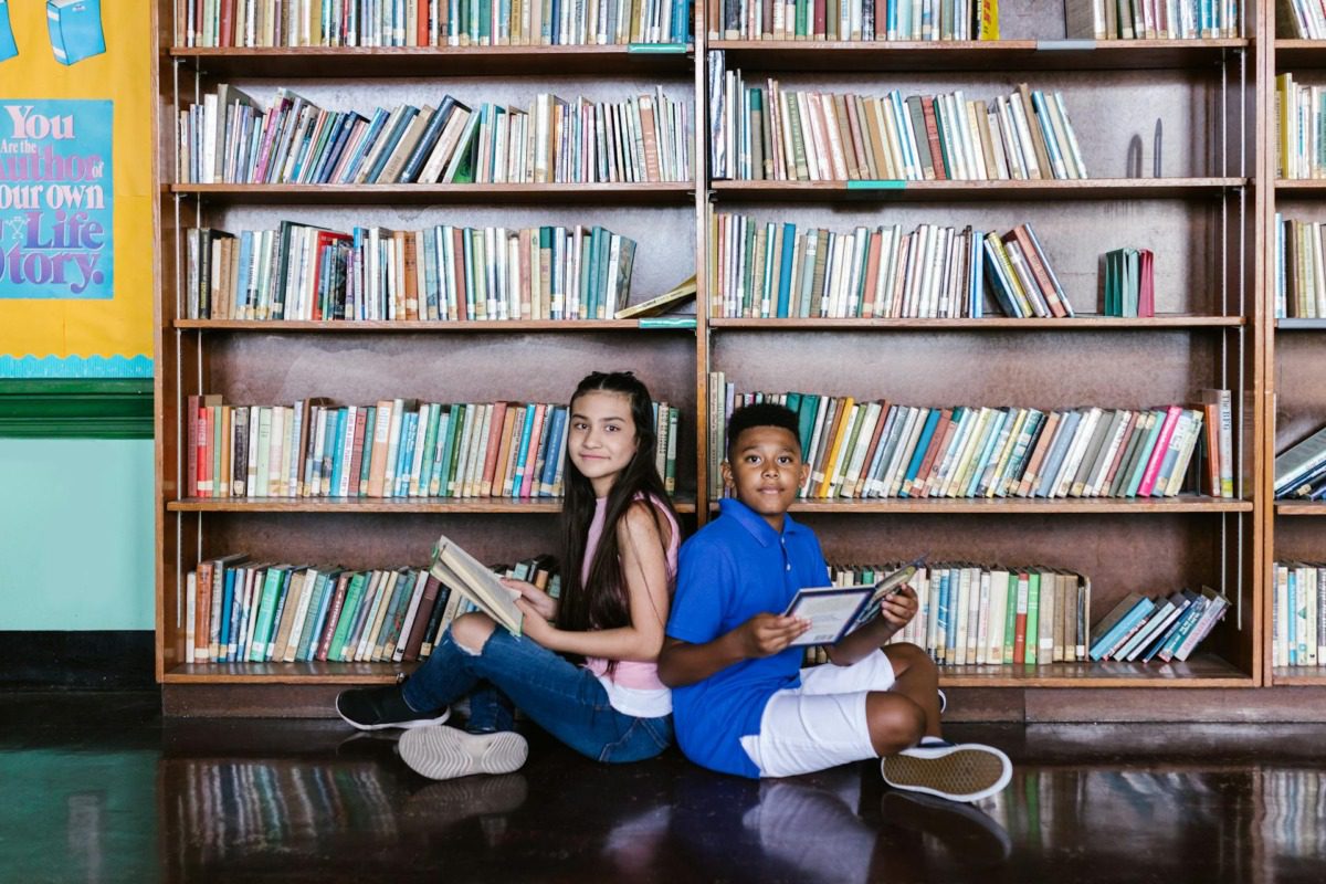 Kids reading in front of a large bookshelf 