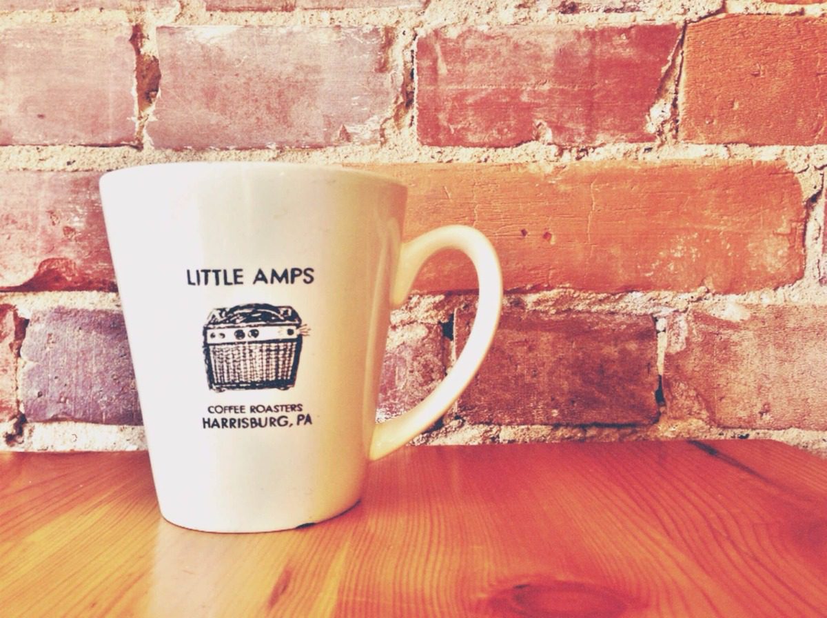 Little Amps coffee cup against brick wall 