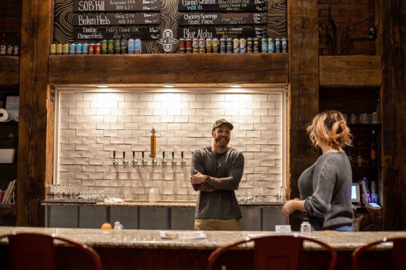 two people stand behind a bar talking